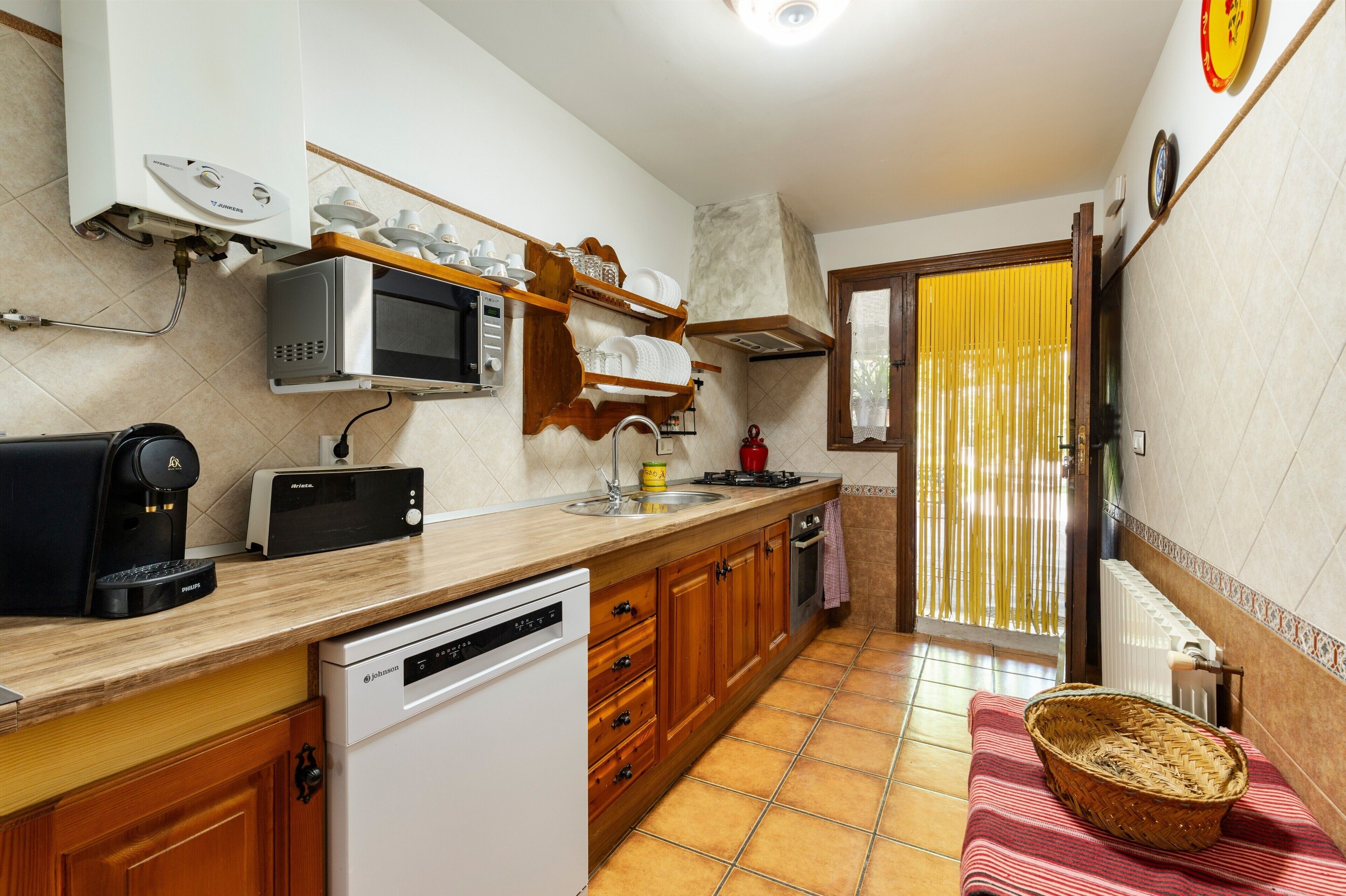 Cocina compacta equipada con lavavajillas, microondas y cafetera.