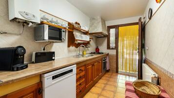 Cocina compacta equipada con lavavajillas, microondas y cafetera.