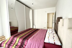 A bedroom with a bed, a wardrobe, and a mirror. - P034 - Porto Recanati, new three-room apartment with garden (Porto Recanati)