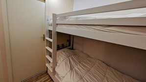Ein Etagenbett mit einer Leiter, einer Tür und einem Regal.