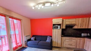 Ein kompakter Wohnbereich mit Sofa, Küchenzeile und Essplatz.