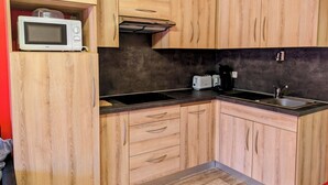 Eine kleine Küche mit Holzausstattung, einer Mikrowelle, einem Toaster und einer Kaffeemaschine.