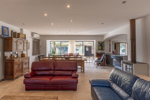 Un salon spacieux avec un canapé en cuir rouge, un canapé en cuir bleu et un coin repas doté de meubles en bois.
