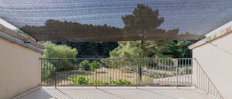 A balcony with a mesh shade, metal railing, and two green chairs.
