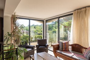 Un salon moderne avec de grandes fenêtres, un canapé, un fauteuil et une table.