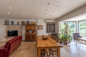 Un vaste espace de vie comprenant une grande table à manger en bois, un canapé en cuir rouge, un téléviseur et une cheminée.