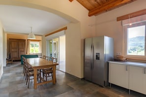 A modern kitchen with a large island, stainless steel appliances, and a view of the outdoors.