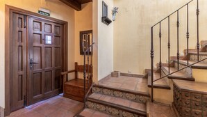 A wooden door with a sign, a staircase with ornate railings, and a wall-mounted light fixture. - Holiday Home 'Casa Alval' with Mountain View, Wi-Fi and Air Conditioning (VILLACASTIN)