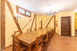 A dining area with a wooden table and chairs, a chandelier, and a door with a fire extinguisher. - Holiday Home 'Casa Alval' with Mountain View, Wi-Fi and Air Conditioning (VILLACASTIN)