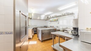 A commercial kitchen with stainless steel appliances, a coffee maker, and tiled walls. - Holiday Home 'Casa Alval' with Mountain View, Wi-Fi and Air Conditioning (VILLACASTIN)