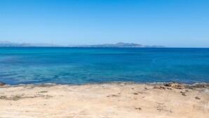 A coastal landscape with clear blue water, rocky shore, and distant mountains. - Holiday Home 'Es Mirador' with Sea View, Wi-Fi and Air Conditioning (Son Serra de Marina - Santa Margalida)