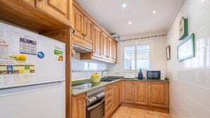 A kitchen with wooden cabinets, a refrigerator, an oven, a microwave, and a window. - Holiday Home 'Es Mirador' with Sea View, Wi-Fi and Air Conditioning (Son Serra de Marina - Santa Margalida)
