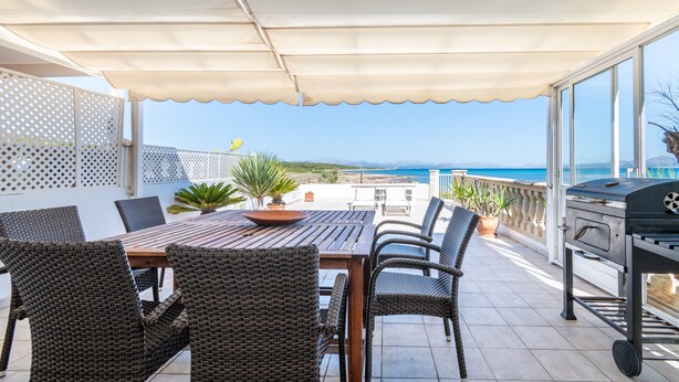 An outdoor patio with a table and chairs, a grill, and a view of the sea. - Holiday Home 'Es Mirador' with Sea View, Wi-Fi and Air Conditioning (Son Serra de Marina - Santa Margalida)