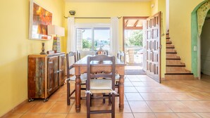 A dining area with a wooden table and chairs, a cabinet, and a view through a glass door. - Holiday Home 'Es Mirador' with Sea View, Wi-Fi and Air Conditioning (Son Serra de Marina - Santa Margalida)