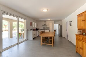 Une cuisine moderne avec un coin repas, des portes-fenêtres coulissantes donnant sur une terrasse et un meuble en bois.