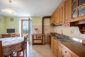 A kitchen with wooden cabinets, a sink, and a dining area with a table and chairs.