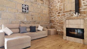 A room with a stone wall, a fireplace, a sofa, and a framed picture.