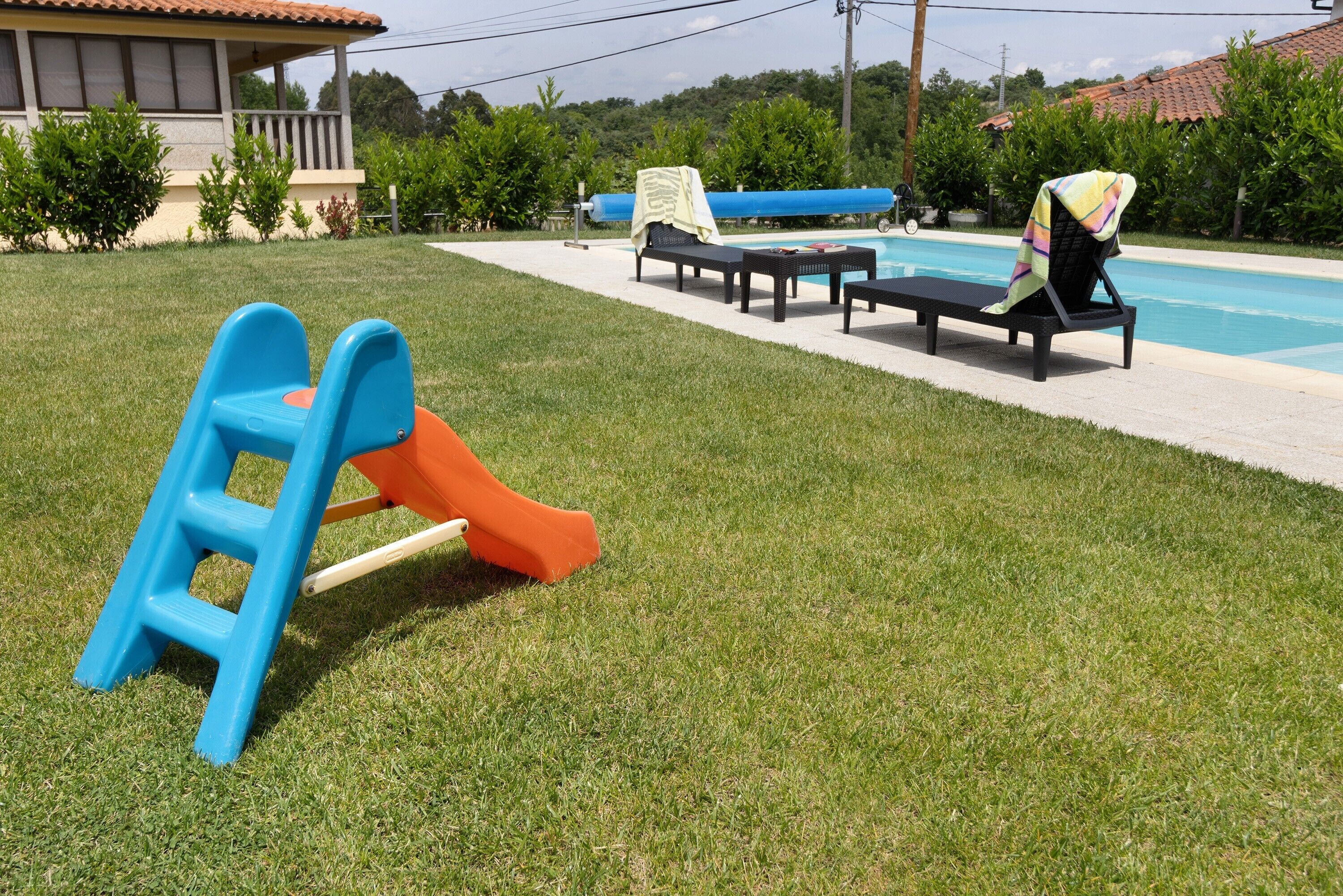 A poolside area with a slide, lounge chairs, and a small table.