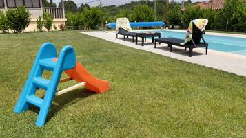 A poolside area with a slide, lounge chairs, and a small table.