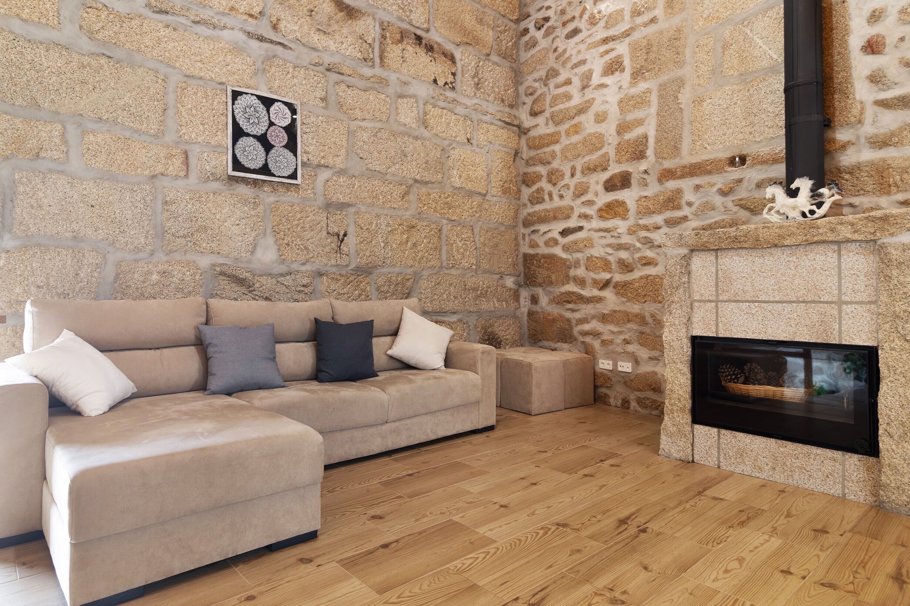 Une pièce avec un mur en pierre, une cheminée, un canapé et un tableau encadré.
