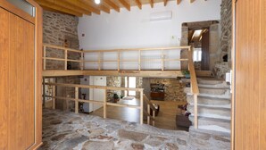 Ein mehrgeschossiges Holzinnere mit Steinfußboden, einer Treppe und einer Küchenzeile.