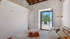 Un dormitorio con cama, toallas, una ventana y vistas al exterior.