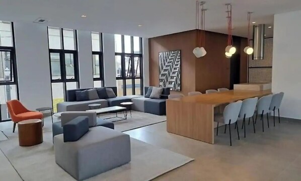 Een moderne woonkamer met een grote hoekbank, een houten salontafel en een eethoek met een lange tafel en stoelen.