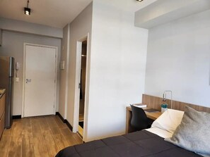 Een hotelkamer met een bed, een bureau, een stoel en een kledingkast.
