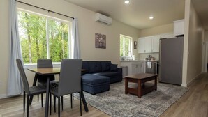 A modern living room with a dining table, sofa, and kitchen area. - Lovely Condo close to town with Forest View (Longview)