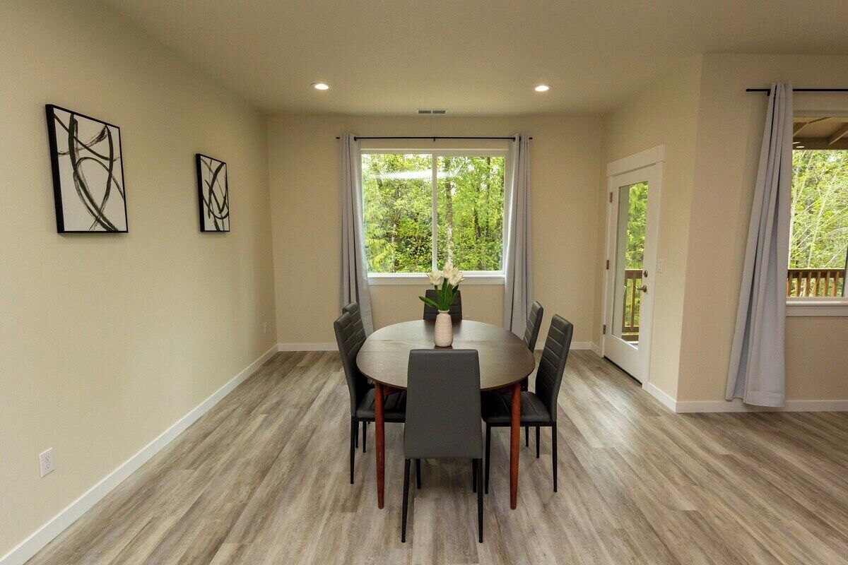 A dining area with a round table, six chairs, and two abstract paintings on the wall.