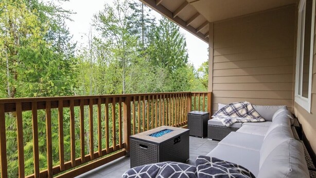 A balcony with a wooden railing, a sofa, a small table, and a basket. - Spacious home and lower level condo with outside entrance. (Longview)
