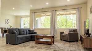 A modern living room with a sectional sofa, a coffee table, and a television. - Spacious home and lower level condo with outside entrance. (Longview)