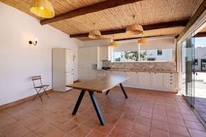 A kitchen with a wooden table, white cabinets, and a tiled floor. - Apartment 'Monte Gerações 2' with Shared Pool, Wi-Fi and Air Conditioning (Almancil)