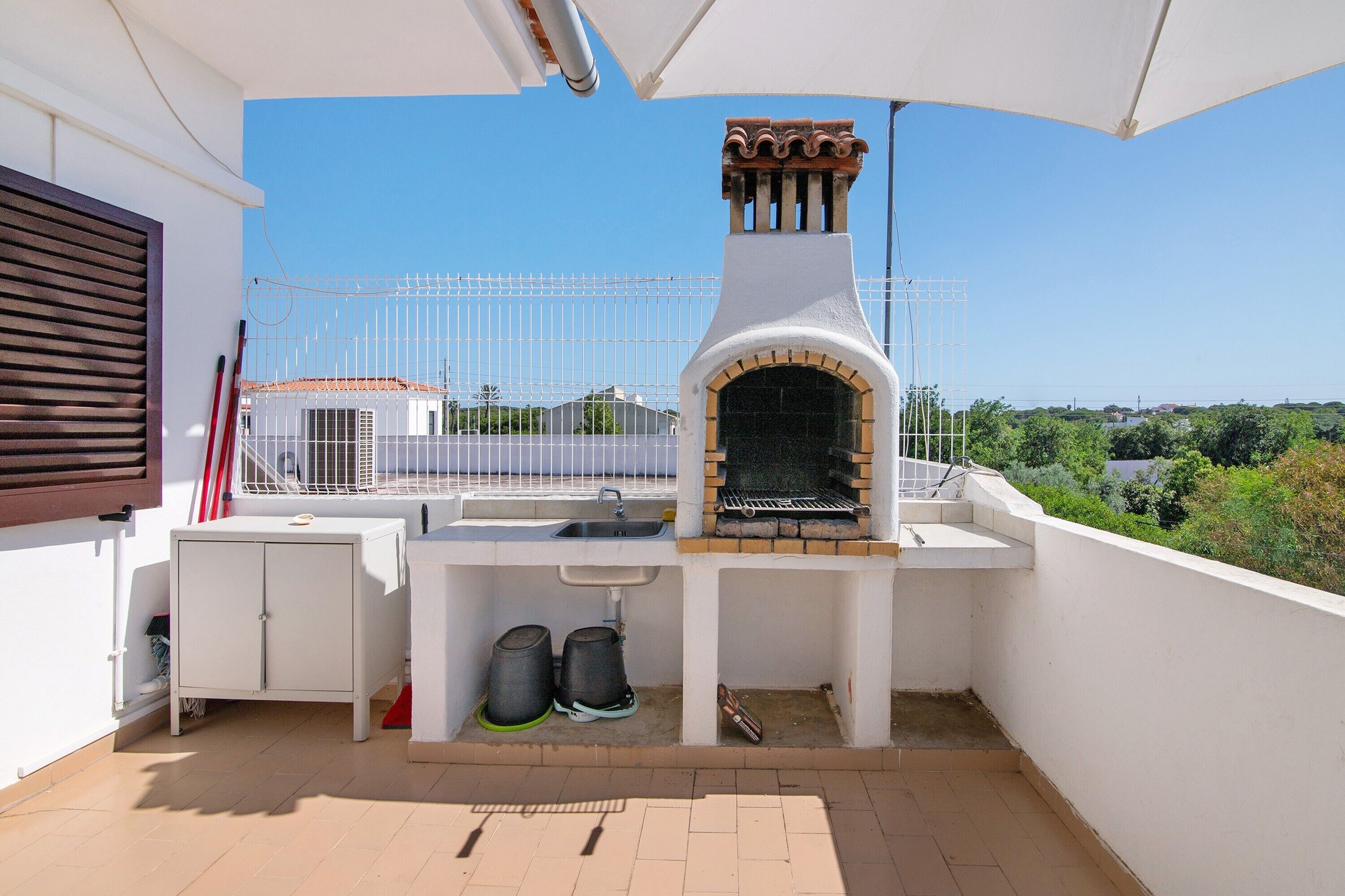 A balcony with a built-in grill, a sink, and a storage cabinet.