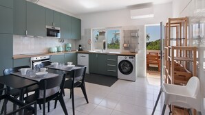 A modern kitchen with a dining area, a washing machine, and a view of the outdoors.