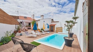 Uma área de piscina com espreguiçadeiras, plantas em vasos e céu claro.