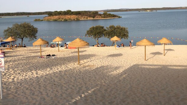 Uma praia com guarda-sóis de palha e areia dourada.