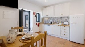 A kitchen with white cabinets, a tiled backsplash, and a white refrigerator. - Apartment 'Monte Gerações 4' with Shared Pool, Wi-Fi and Air Conditioning (Almancil)