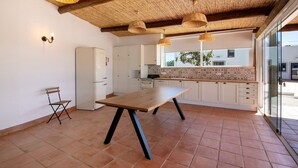 A kitchen with a wooden table, white cabinets, and a tiled floor. - Apartment 'Monte Gerações 4' with Shared Pool, Wi-Fi and Air Conditioning (Almancil)