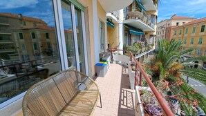 Un balcone con mobili in vimini, un tavolino e piante in vaso.