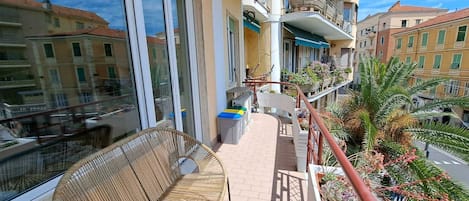 A balcony with wicker furniture, a small table, and potted plants.