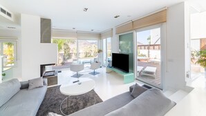 Ein modernes Wohnzimmer mit Sofa, Couchtisch, Fernseher und großen Fenstern.