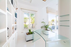 Un interior modern amb parets blanques, una taula de vidre i plantes en testos.