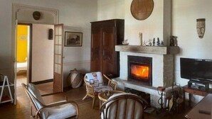 A cozy living room with a fireplace, wooden furniture, and a television. - 164Gourbets - Belle villa des années 20 pour 14 personnes à Biscarrosse Plage (BISCARROSSE)