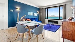 Un comedor con una mesa, sillas y vistas al mar a través de amplios ventanales.