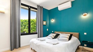 Un dormitorio con cama, cortinas, una ventana y una pared color turquesa.