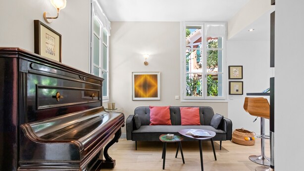 Une pièce comprenant un grand piano, un canapé avec des coussins, une petite table ronde et une lampe.