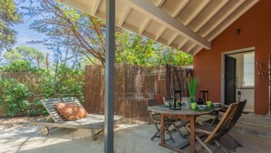 Une terrasse extérieure couverte, avec une table et des chaises, un fauteuil de relaxation et une clôture en bois.