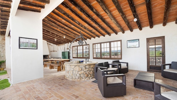 An outdoor patio with stone flooring, wicker furniture, and a stone island with a sink. - Country House 'Cal Eloi Janet' with Mountain Views, Private Pool and Wi-Fi (Sant Marti Sarroca)