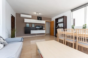 Un salon moderne comprenant un canapé, un téléviseur, une table à manger et des chaises.